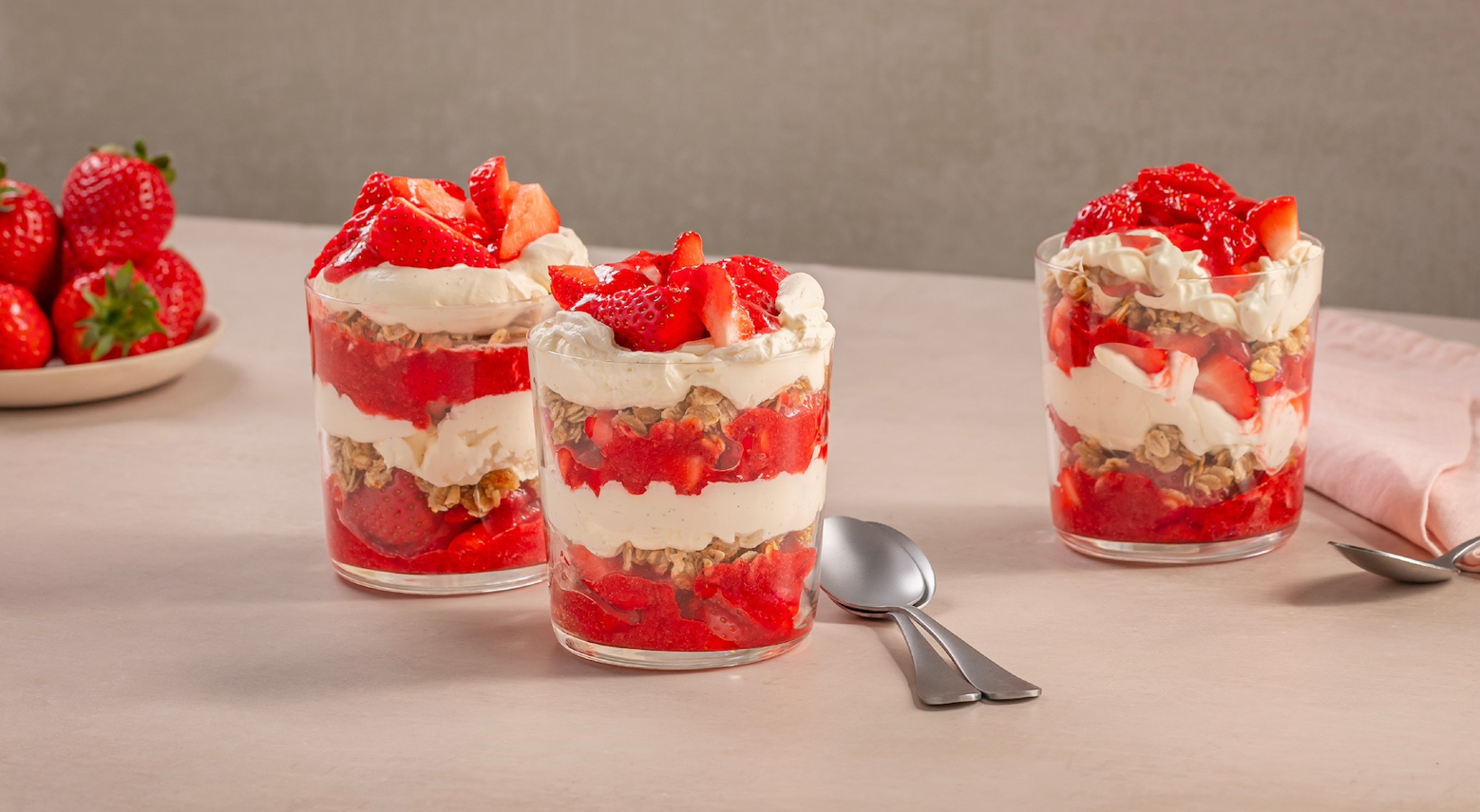 three glass bowls of dessert with cream and strawberries